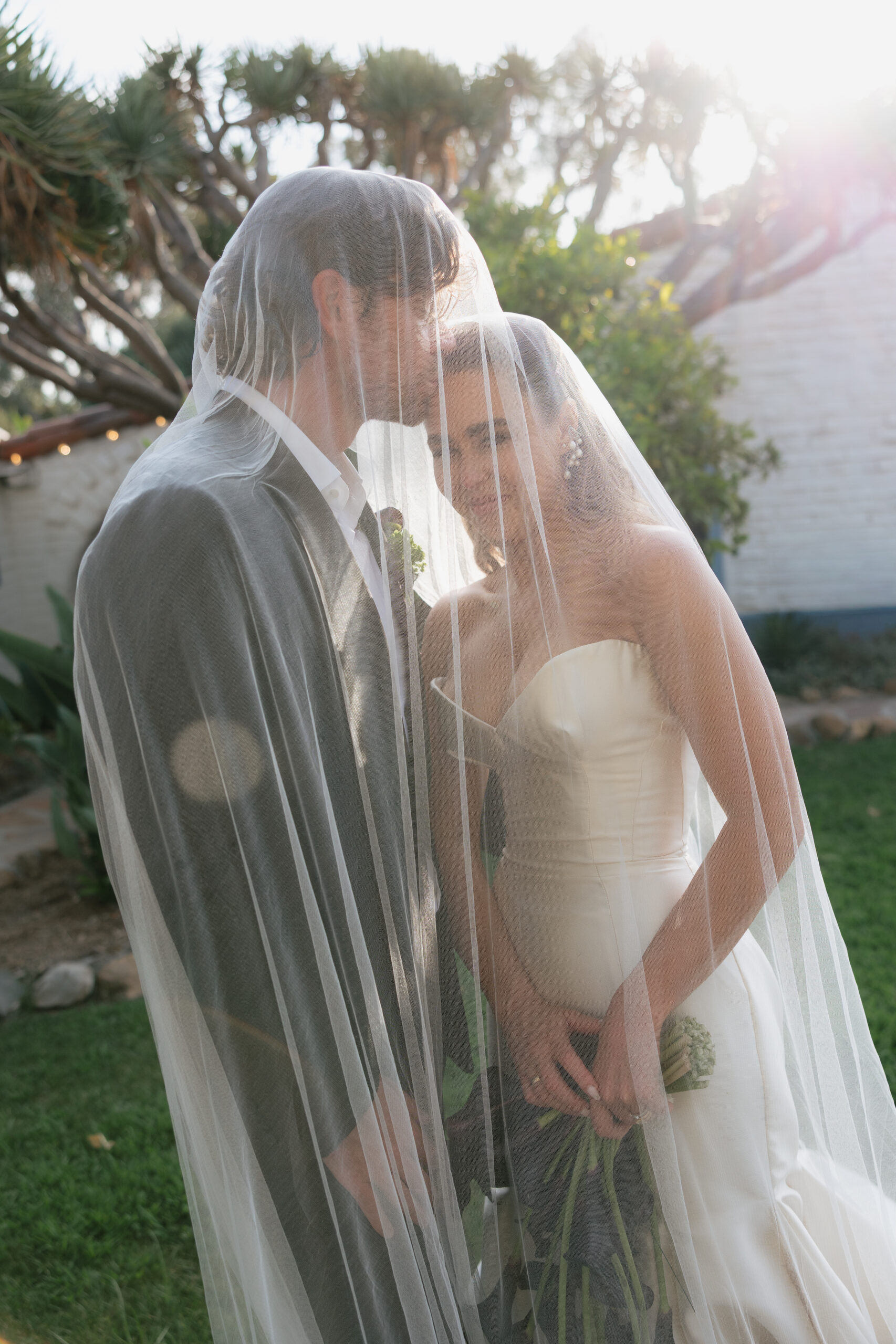 Sara and Taylor’s romantic Leo Carrillo Ranch wedding portrait under a veil at golden hour in Carlsbad, California