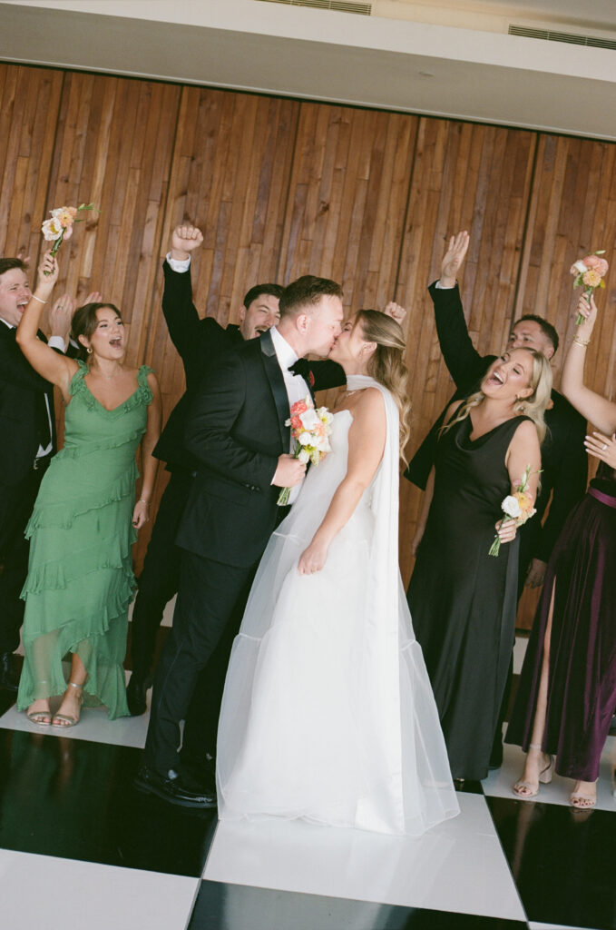 Film photograph of Ben and Lauren kissing surrounded by their wedding party