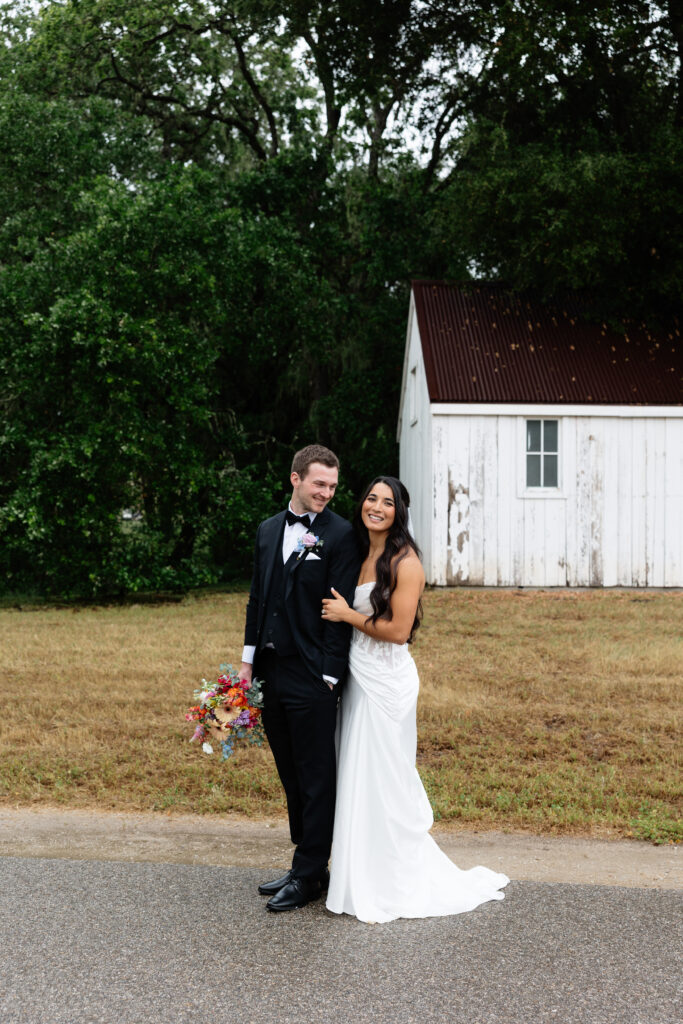 Bride and groom walking together on the road outside a white barn at Halter Ranch