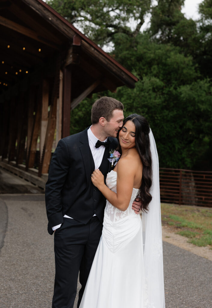 Bride and groom embracing outside the covered bridge at Halter Ranch after the rain