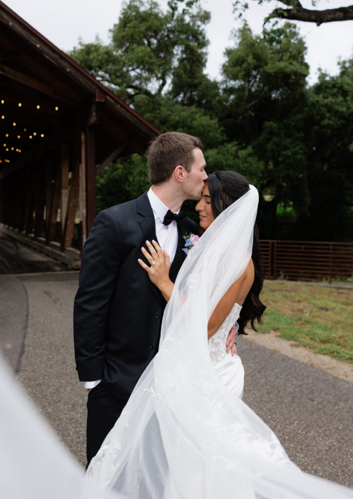 Bride and groom sharing a kiss beneath the covered bridge at Halter Ranch