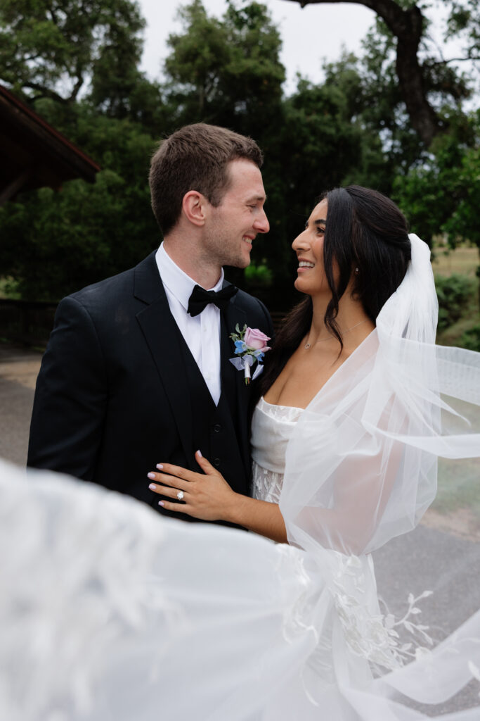Bride and groom smiling at each other in front of the vineyard landscape