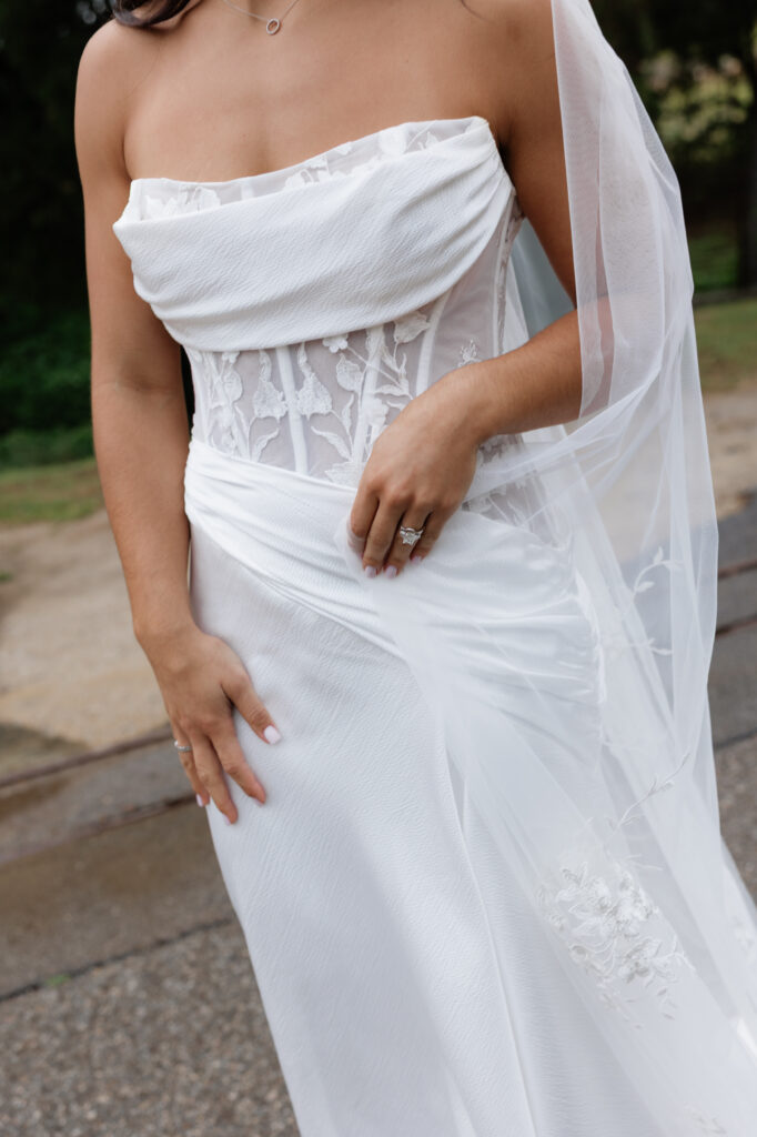 Close-up of bride’s white wedding dress, lace bodice, veil, and engagement ring