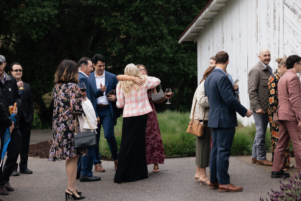 Wedding guests mingling with drinks outside the barn during cocktail hour
