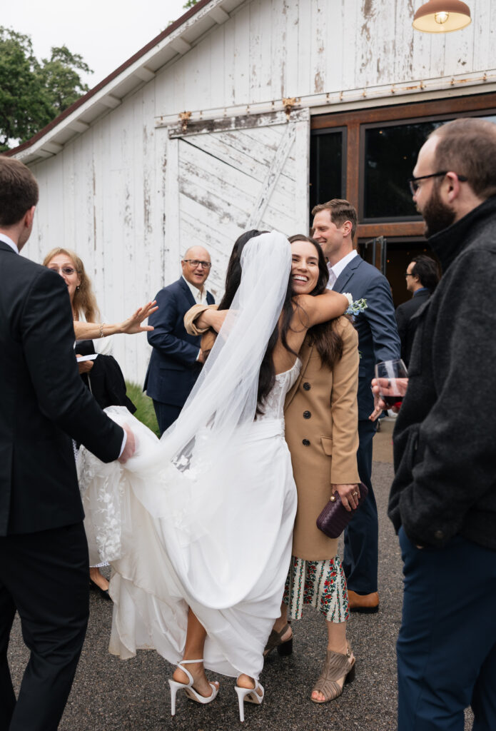 Bride greeting and embracing wedding guests outside the Halter Ranch barn