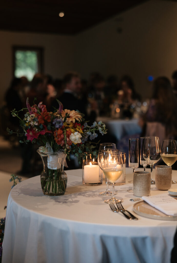 Colorful floral centerpiece and candlelit place setting at the Halter Ranch wedding reception
