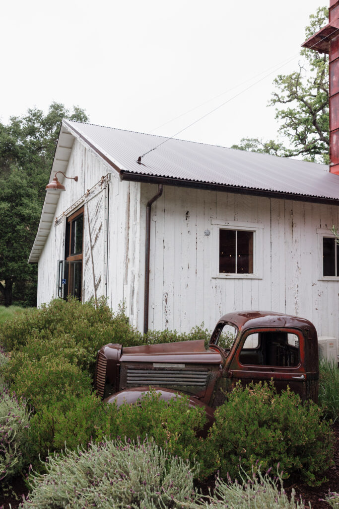 Vintage truck surrounded by greenery outside the white barn at Halter Ranch