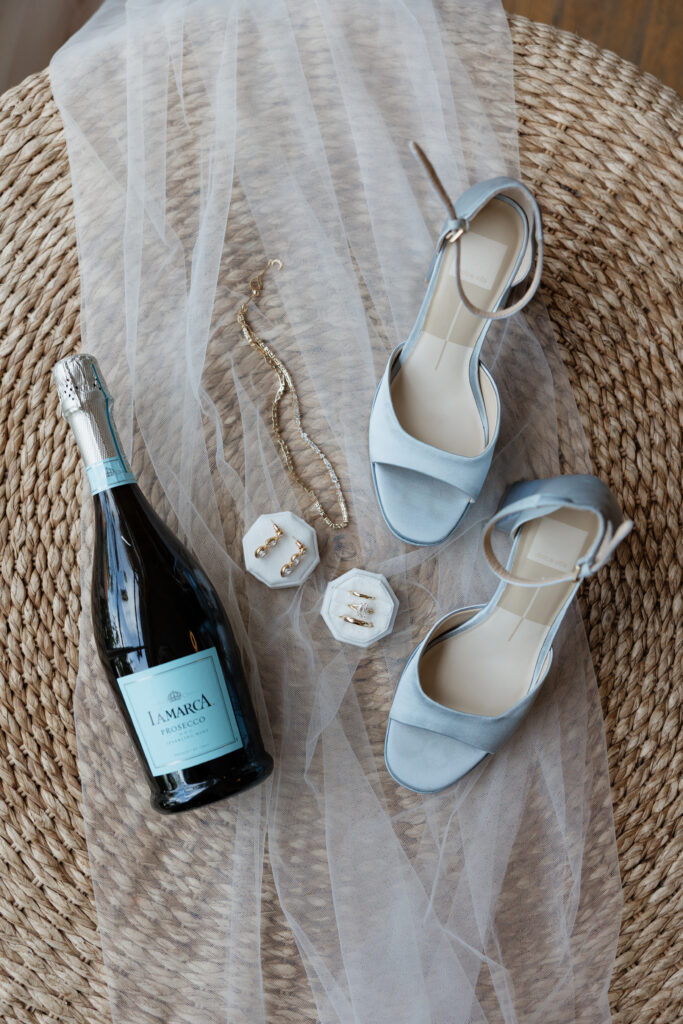 Bride’s blue wedding shoes, veil, jewelry, and champagne details