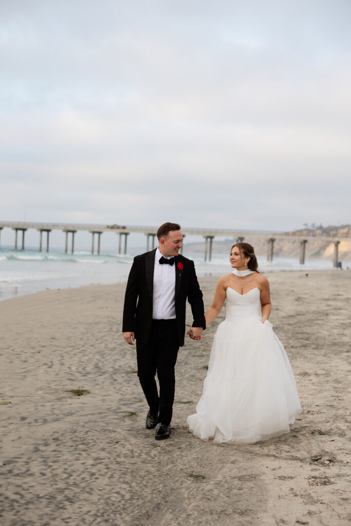 Ben and Lauren walking together along the beach with the Scripps Pier in the background