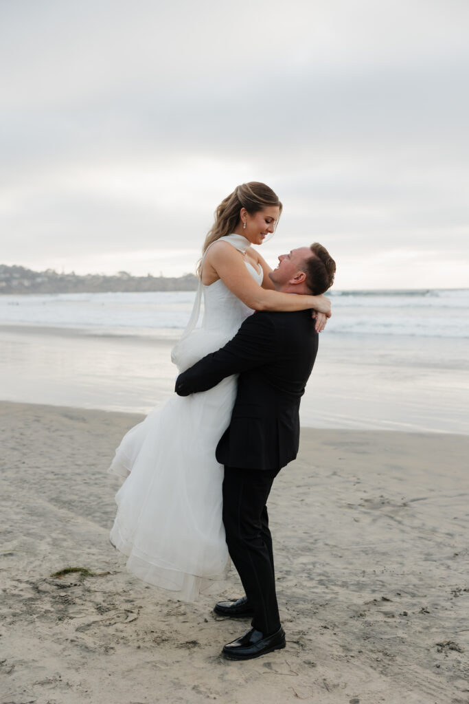 Ben lifting Lauren in a playful beach wedding portrait