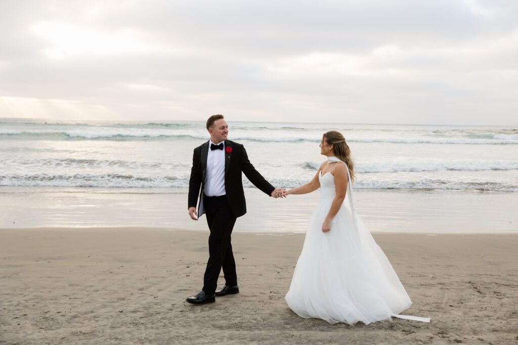 Ben and Lauren walking together along the beach during their La Jolla wedding

